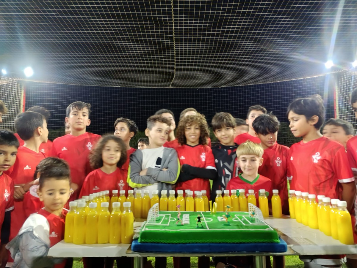 Les joueurs autour d'un gâteau en forme de terrain de football, lors d'une fête de l'Academy